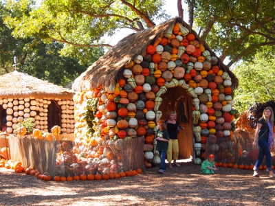 [Buildings with thatched roofs and sidewalls constructed to appear if they are comprised completely of stacked gourds. One building is multi-colored gourds while another is all white gourds.]